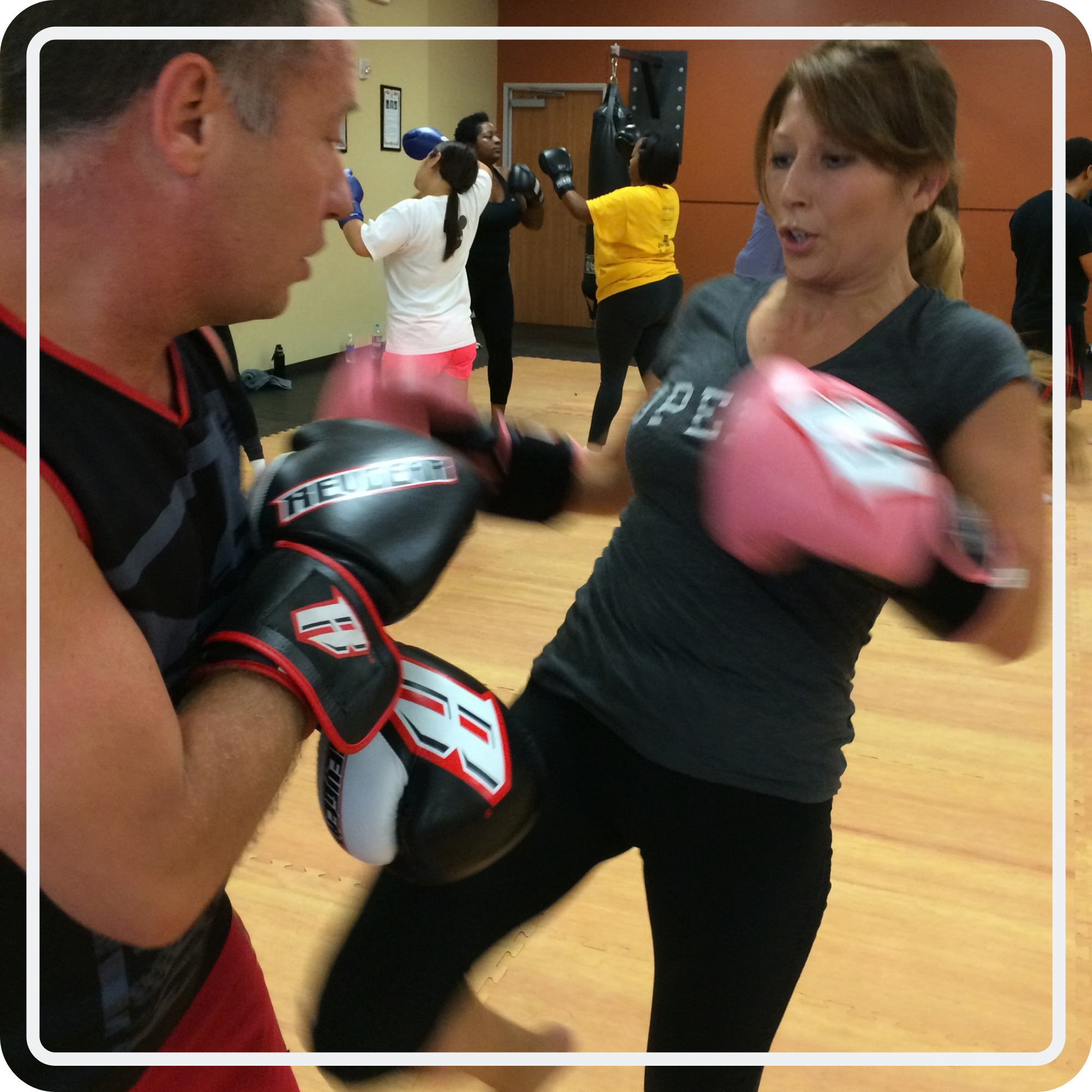 An Inspire kickboxing student practicing punches with a partner holding focus mitts